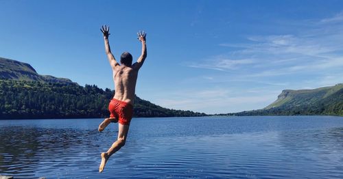 Full length of woman jumping in sea against sky