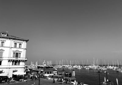 Sailboats moored in harbor against clear sky