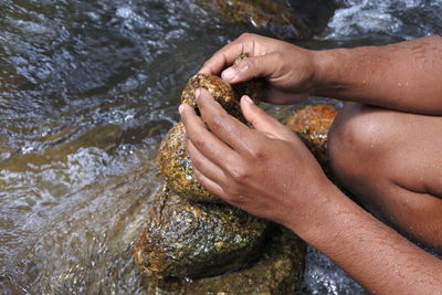 Midsection of man stacking stones by river