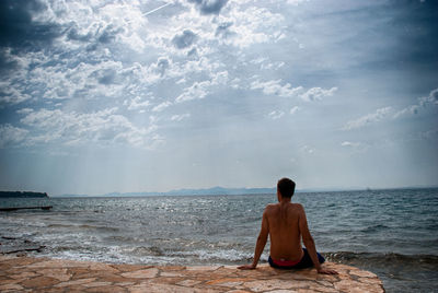 Rear view of man sitting on beach