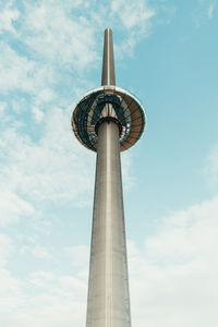 Low angle view of communications tower against cloudy sky