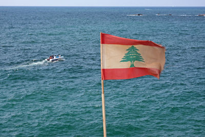 Scenic view of flag on sea against sky