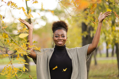 Portrait of smiling young woman standing by plants