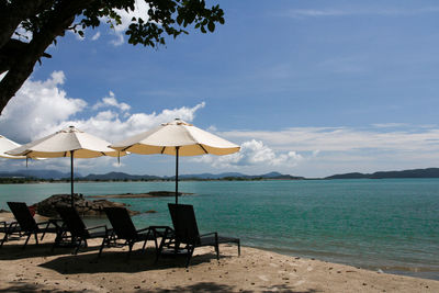 Deck chairs on beach against sky