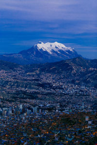 Aerial view of townscape and mountains against sky