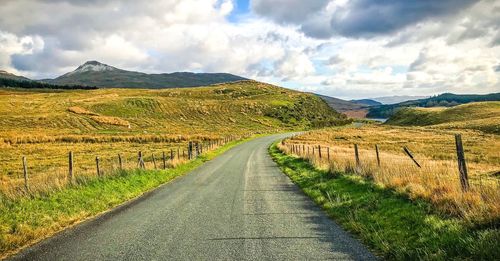 Road leading towards mountains against sky