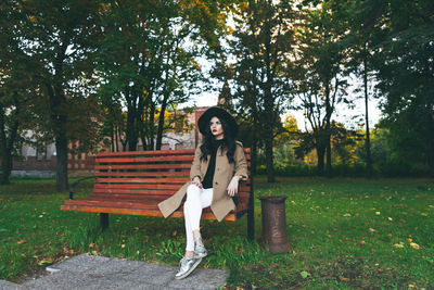 Portrait of woman sitting on bench in park