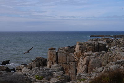 Scenic view of sea by rock formation against sky