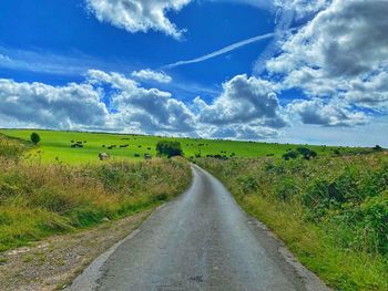 Road amidst field against sky