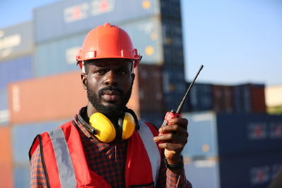 Side view of man holding hardhat while standing in factory