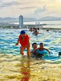 Full length of father and daughter in sea against sky