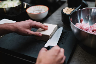 From above anonymous chef cutting piece of fresh cheese near bowl with meat during cooking lesson in restaurant kitchen in navarre, spain person