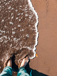 Low section of man standing on beach