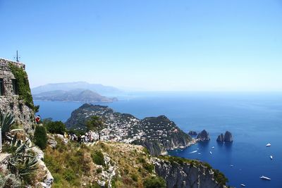 Scenic view of sea and mountains against clear blue sky