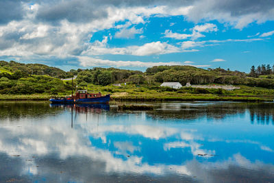 Scenic view of clifden bay at high tide against blue sky with a fishing boat anchored in the water