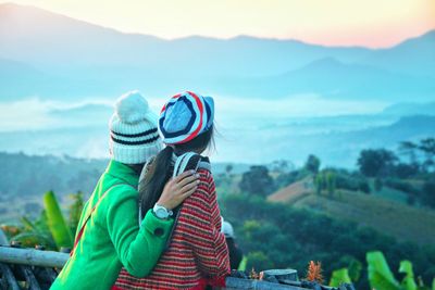 People looking at mountains against sky