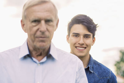 Portrait of young man smiling with grandfather in foreground