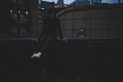 Side view of woman standing on city at night