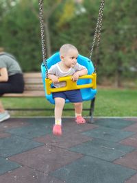 Full length of baby boy sitting on swing at park