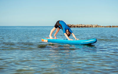 Side view of man in sea against clear sky