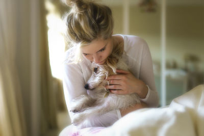 Young woman cuddling dog at home