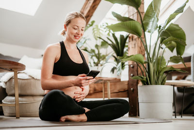 Young woman using mobile phone while sitting on table