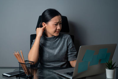 Young woman using mobile phone while sitting on table