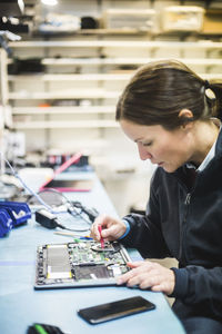 Female engineer repairing computer equipment in workshop