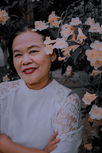 Portrait of woman standing by lowering plant