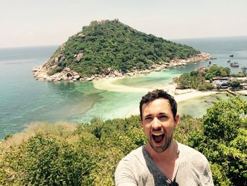 Portrait of happy man standing against sea