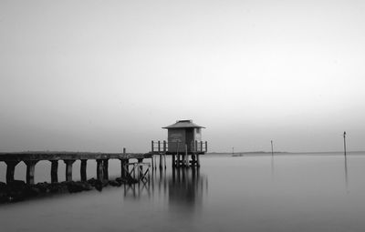 Lifeguard hut in sea against sky during foggy weather