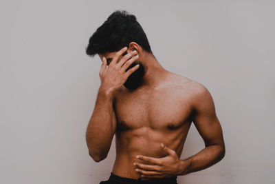 Midsection of shirtless man against white background