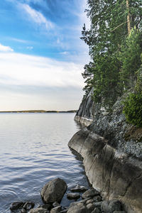 Scenic view of rocks by sea against sky