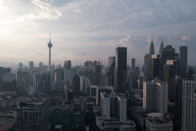 Aerial view of buildings in city against cloudy sky