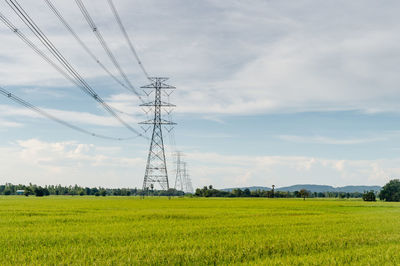 Electricity pylon on field against sky