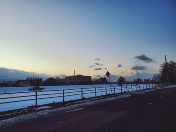 Road by railing against sky during winter