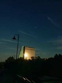 Street light by building against sky at night