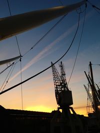 Low angle view of silhouette cranes against sky during sunset