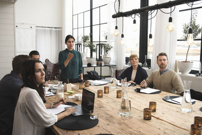 Businesswoman explaining to colleagues during meeting at table in office