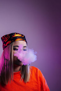 Portrait of woman with pink hair standing against colored background