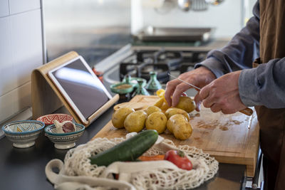 Senior man chopping potatoes on cutting board in kitchen