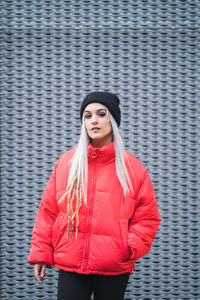 Portrait of beautiful young woman standing against wall