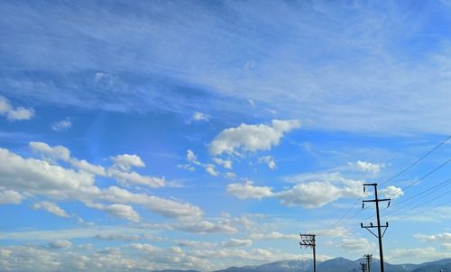 Low angle view of electricity pylon against blue sky