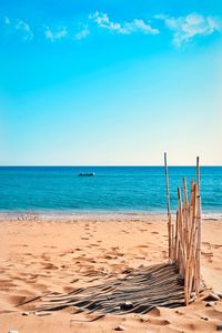 Wooden posts on beach against sky