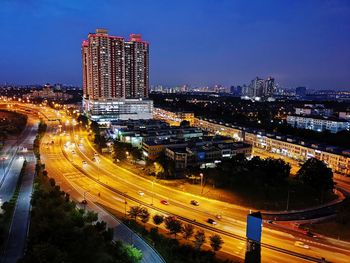 High angle view of illuminated street amidst buildings in city at night