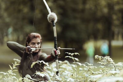 Archer holding bow and arrow standing on field