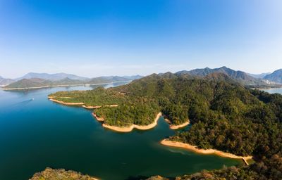 Scenic view of lake and mountains against clear blue sky