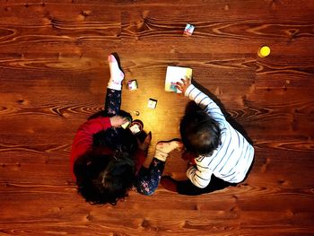 High angle view of siblings playing with toy on hardwood floor at home