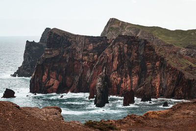 Rock formation by sea against clear sky