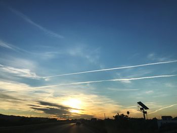 Scenic view of silhouette vapor trail against sky during sunset